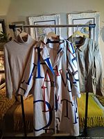 Three garments on rack: cashmere sweater, printed coat, faux leather jacket