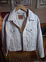 Front view of off-white Levi's denim jacket on hanger