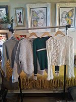 Rack view of four sweaters hanging on wooden hangers