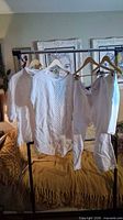 Rack with two white shirts, white crop pants and white shorts