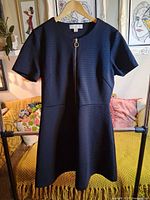 Front view of black Michael Kors dress on hanger showing gold-tone zipper