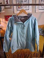 Full view of robin egg blue hooded rain jacket on hanger