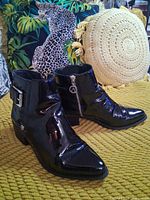 pair of black patent ankle boots angled view on cushion