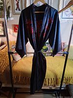 Full view of black satin robe on hanger showing front and belt