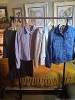 Overall shot of four hanging garments: beige blazer, denim jacket, lavender dress/shirt, black skirt