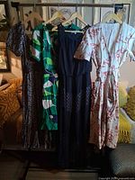 Four dresses hanging on rack showing front designs and lengths