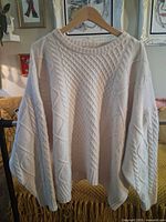 Full front view of ivory cable knit sweater on hanger