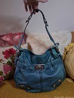 Front view of turquoise leather shoulder bag hanging