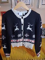 Front view of black wool cardigan with reindeer and snowflake motifs