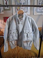 Front view showing light wash denim jacket with stand collar, zip and snap placket, large flap pockets, elastic hem