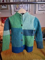 Front view of wool button-up sweater on hanger