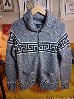 Full view of cardigan on hanger showing front, pattern, pockets and zipper