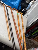 Five assorted vintage wooden canes laid side-by-side on table