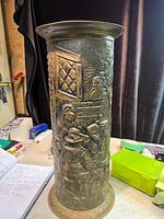 Front view showing tavern scene relief on brass umbrella stand