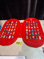 Open red case showing both sides filled with Mighty Beanz capsules