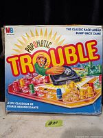 Front of Pop-O-Matic Trouble box showing game title, artwork and MB logo