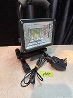 Front view of LED floodlight on stand with charger cord
