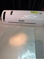 Front view of white Scotch TL902 laminator with stack of pouches in foreground