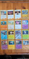 First set of 18 Pokémon cards laid out in a 6×3 grid on wood table