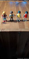 All four Playmobil figures standing on wooden surface