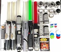 Group view of seven lightsabers with blades, remote, hilt parts, colour lenses and booklet