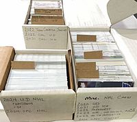 Three long storage boxes filled with sorted hockey cards, labeled by set and year