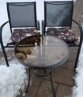 Full view of two chairs and table on patio with snow