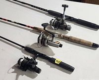 Three spinning rod and reel combos laid out on table