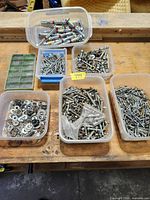 Overview of lot in multiple containers containing screws, nuts, washers and sleeve anchors