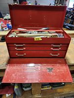 Open red toolbox displaying drawers and assorted tools