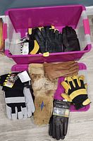 Two storage bins holding assorted gloves pairs, some tagged