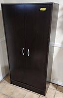 Front view of cabinet with doors closed showing black finish and handles