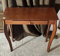 Full view of brown veneer side table showing top, drawer, and legs