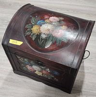 Angled view showing curved lid, floral painting, side handle
