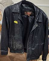 Full front view of black leather Danier jacket on hanger