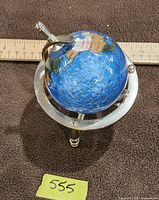 Front view of gemstone globe on stand with ruler for scale