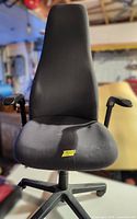 Front view of black fabric high-back office chair showing seat, backrest, armrests and rolling base