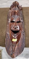 Front view of elongated carved wooden wall mask