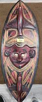 Front of carved wooden mask showing face, fish figures, geometric patterns
