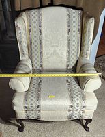 Front view of wingback chair showing upholstery pattern, seat width taped, wood legs