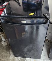 Front view of black Kenmore compact refrigerator showing overall condition and scratches