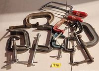 Top view of eight assorted C-clamps and two coping saws laid out
