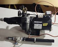 Side view of Mastercraft jet pump showing motor label, pressure switch, barb fittings, attached wires, inline pipe section beside unit