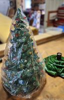 Ceramic Christmas tree wrapped in plastic next to green base