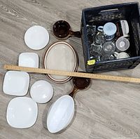 All dinnerware, glassware and crate laid out with ruler for scale