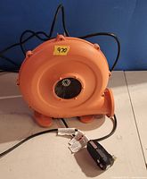 Front view of orange air mover showing blower housing and intake grill