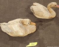 Two carved duck figurines displayed side by side