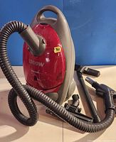 Full view of red Samsung canister vacuum with hose and attachments