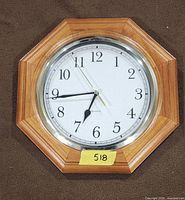 Front view of octagon wood-tone wall clock displaying dial and hands