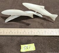 Three bone fish carvings displayed with ruler for scale